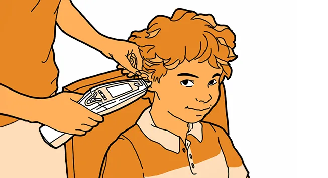 A young Aboriginal boy, smiling while having his ear checked with a medical device.