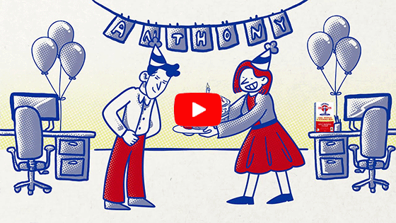 Woman handing man a cake in an office setting. Click to play video.